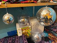 Group of five mirror disco balls on shelf, boxes visible