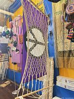 Rope hammock hung in front of purple peace flag, additional rolled hammocks visible