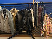 Group shot showing three jackets, umbrellas and scarves hanging on railing