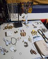Loose jewelry on tabletop and stand showing variety of types and materials