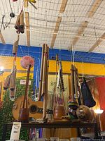 Overall view of hanging and shelved wooden instruments including guitar, flutes, panpipes, maracas and chimes