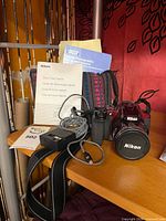 Camera with manuals, charger, strap and bag on shelf