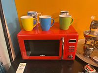 Front angled view showing red Salton microwave with mugs on top (props)