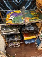 Shelving rack holding multiple folded printed fabric scarves packaged in plastic sleeves