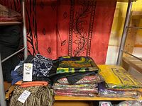 Stack of assorted silk scarves on shelf, various colours in packaging
