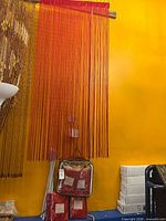 Full view of one red string curtain hanging from rod