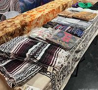 Overall view of folded tapestries, blanket, hats on table