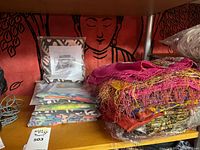Stacked scarves and tapestry visible on shelf