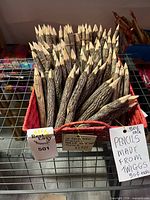 Basket filled with twig pencils showing natural bark and sharpened tips, price tags visible
