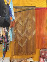 Hanging wood bead curtain with diamond motif beside another orange strand curtain