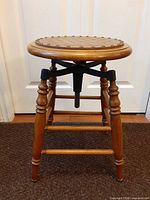 Full view of wooden swivel stool showing legs, seat and cast iron adjuster