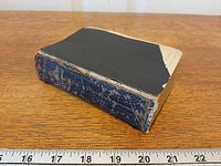 Side view of Bible showing missing cover and size against ruler