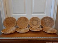 Eight wicker chargers lined up showing fronts and side profile
