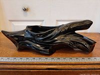 Full side view of glossy black ceramic driftwood planter with ruler for scale