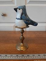 Full view of candle on brass stand with ruler for scale