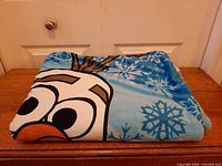 Folded Olaf blanket showing character graphic and snowflakes