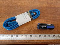 Extension cord coiled with sleeve and multi-tool beside ruler
