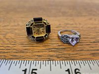 Front view of gold-tone finger watch and silver-tone amethyst ring