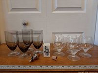 Group shot of four smoky goblets, four crystal brandy glasses, boxed wine stopper