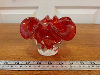 Front view of ruby red art glass bowl with ruler for scale