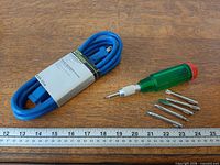 Both items side by side: coiled blue extension cord with sleeve; green Lutz screwdriver with six loose bits; ruler for scale