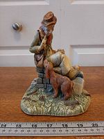 Front view of figurine showing man, dog, base and milestone