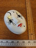 Top view of lidded Pierrot face dish beside ruler showing size