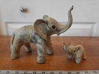 Large and small elephant figurines side by side showing size difference and marbled texture