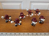 All seven California Raisins figurines lined up on tabletop with ruler for scale