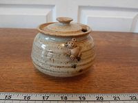 Front view of stoneware honey pot with teddy bear accent