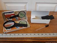 Lot overview with two boxed magnifiers, white box of droppers and loose ruler for scale