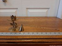 Candle holder and snuffer beside ruler for scale