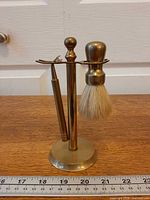 Full view of brass stand with razor and brush, ruler for scale