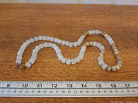 Full view of necklace alongside ruler showing 0-18 in for length reference