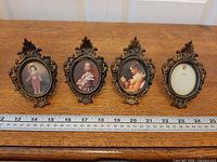 Four ornate oval frames in a row with ruler for scale