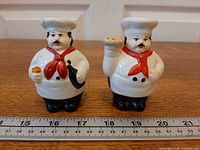 Front view of both ceramic chef shakers beside ruler