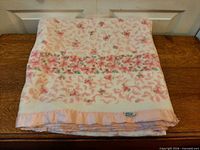 Folded blanket showing floral design and satin trim