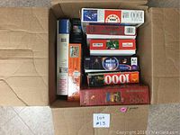 Top view of multiple boxed jigsaw puzzles arranged in a cardboard box showing various pieces and brands.