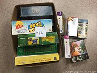 Image showing an open box containing multiple board games and puzzle boxes piled together, including distinct game titles and various puzzle box sizes and designs.