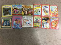 Full view photo of eleven children's books laid out on the floor with colorful covers featuring animals, fairy tales, and educational themes.
