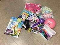 Photo showing assorted craft and activity items including books, balls, scissors, ribbon, and toys on floor.