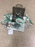 Photo shows a variety of costume jewelry items arranged on a black display and loose in clear plastic bags on a beige floor.