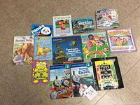 Image showing 14 children's books arranged on the floor with various themes including animals, TV characters (Thomas & Friends), and educational topics.