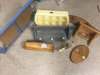 Seven wooden items displayed on floor including wooden shelves, calendar holder, clock, and small decor piece.