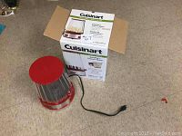 Popcorn maker unit shown with clear plastic cover, red lid, stainless steel base, power cord, and open original box.