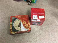 View of both boxed items on the floor: a Christmas Card Clock and a Holiday Entertaining Accessory.
