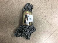 Photo of rolled black and white patterned baby carrier sling in packaging with label and image of woman carrying a baby.