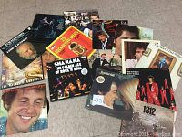 Photo showing assortment of vintage vinyl records on floor, diverse music genres and artists visible including rock and pop.