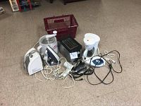 Photo of a group of small kitchen appliances including irons, a toaster, coffee maker, food processor, and a basket container.