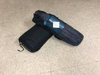 Photo showing two rolled yoga mats in carrying bags placed on a tiled floor. One bag is dark blue, the other black.